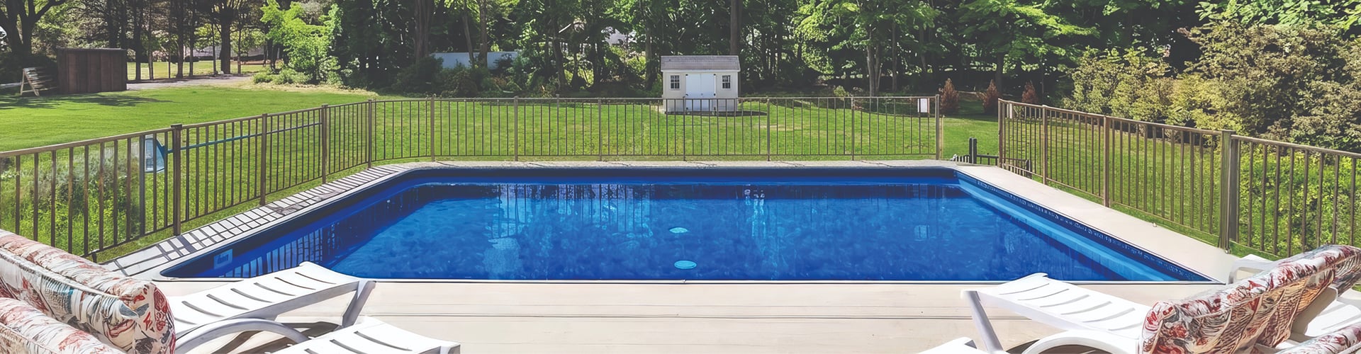 Family relaxing beside a backyard swimming pool at a large house